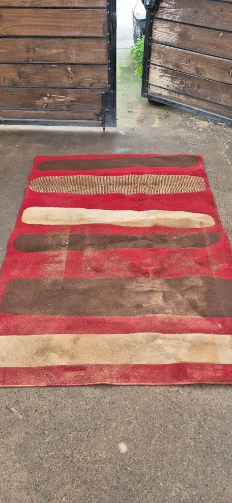 Alfombra roja opaca y sucia antes del lavado